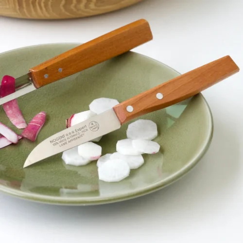 couteau d'office lame 8cm avec un manche en cerisier des bois lame affidenté avec 4 dents par mm dans une assiette avec des radis découpés